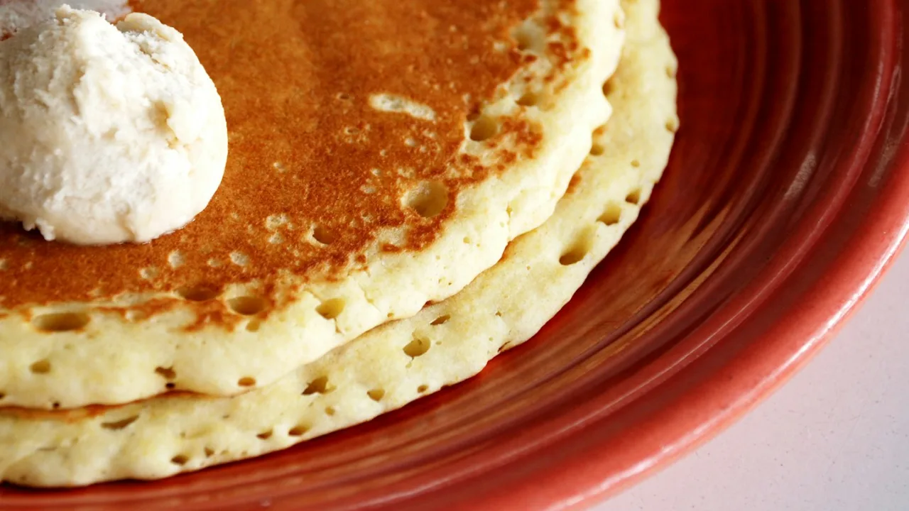 Stacked fluffy pancakes with butter on a plate